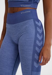Leggings atletici blu con un tessuto testurizzato, vita alta e un motivo a chevron lungo il lato in una tonalità di blu più chiara.