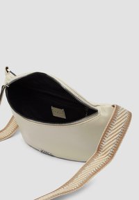 Crème leren schoudertas met een zwarte binnenkant, zilveren hardware en een gevlochten schouderband met beige en metallic accenten. Met ritssluiting.