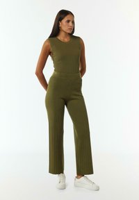 Olijfgroen geribbelde gebreide jumpsuit met een aansluitend tanktop en wijde pijpen, met een gladde textuur en een elastische tailleband.