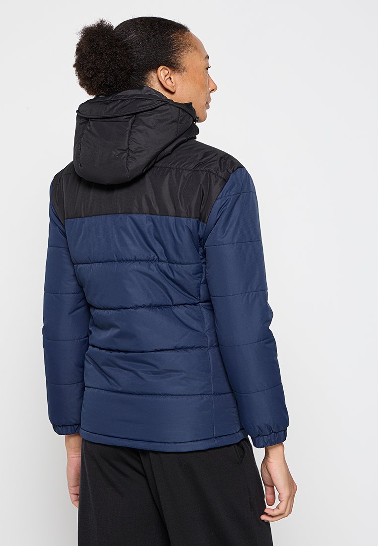 Giacca a vento con corpo blu e dettagli neri, cappuccio, polsini elasticizzati e texture trapuntata. Adatta per il freddo.