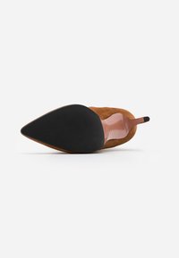 Ruske suknje s ukazivanje prsta, sa visokom potpeticom, prikazane iz perspektive đona, pokazujući crni teksturirani potplat i tanki vrh potpetice.