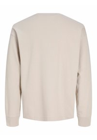 Μπεζ ανοιχτόχρωμο μακρυμάνικο μπλουζάκι με λαιμόκοψη στρογγυλή, που διαθέτει λεία υφή και άνετη εφαρμογή. Οι ραφές είναι ραμμένες και ορατές κατά μήκος των άκρων.