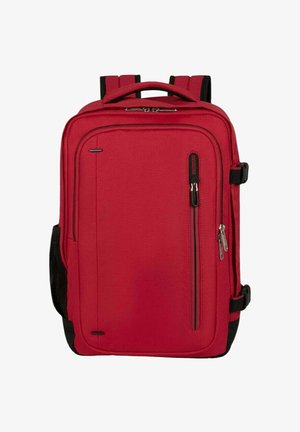 Punainen kangasreppu suorakaiteen muotoisena, jossa on kahdet pehmustetut olkahihnat, etupuolella vetoketjutasku ja mustat kontrastielementit sivuilla.