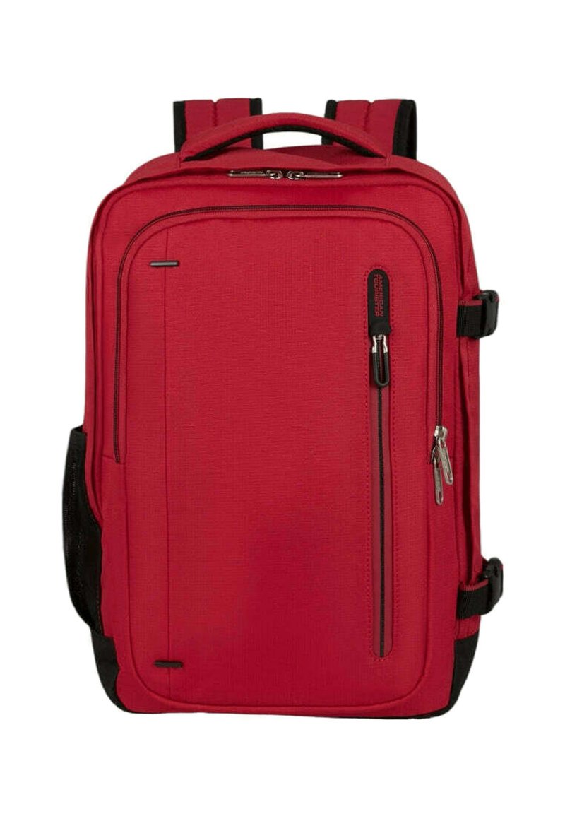 Punainen kangasreppu suorakaiteen muotoisena, jossa on kahdet pehmustetut olkahihnat, etupuolella vetoketjutasku ja mustat kontrastielementit sivuilla.