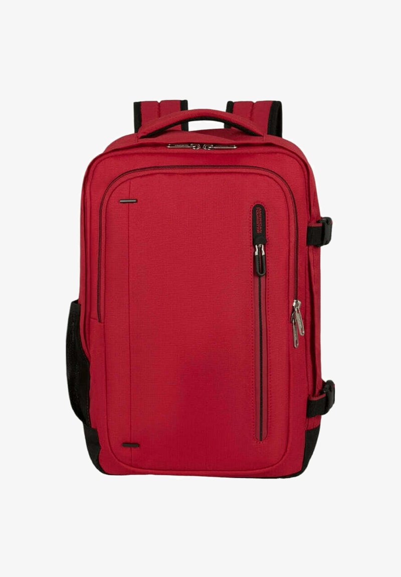 Punainen kangasreppu suorakaiteen muotoisena, jossa on kahdet pehmustetut olkahihnat, etupuolella vetoketjutasku ja mustat kontrastielementit sivuilla.