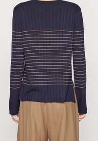 Granatowy prążkowany sweter z poziomymi beżowymi paskami. Posiada okrągły dekolt, długie rękawy oraz lekko wydłużony tylny dół.