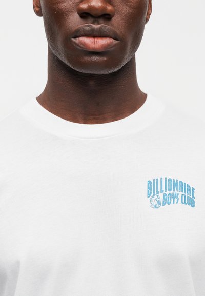 Λευκό βαμβακερό t-shirt με μπλε λογότυπο "Billionaire Boys Club" στο αριστερό στήθος. Στρογγυλή λαιμόκοψη, λεία υφή και κοντά μανίκια.