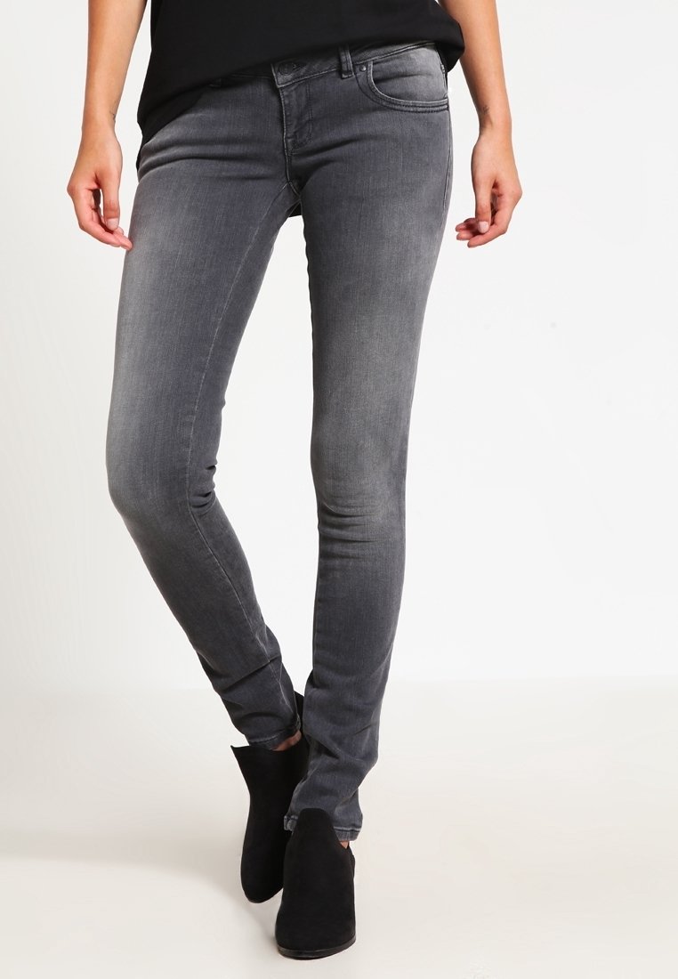 Jeans ajustados grises de mezclilla, con un lavado medio, diseño de cinco bolsillos y detalles de desvanecimiento sutil. Combinados con botas negras hasta el tobillo.