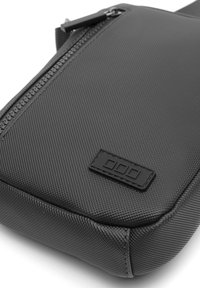 Borsa in tessuto grigio texturizzato con chiusura a zip, forma rettangolare e una patch con logo nera sul lato. Design resistente e funzionale.