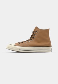 Brune høye sneakers laget av lerret med snøring, hvit gummitåhette og svarte stripe detaljer på sålen.