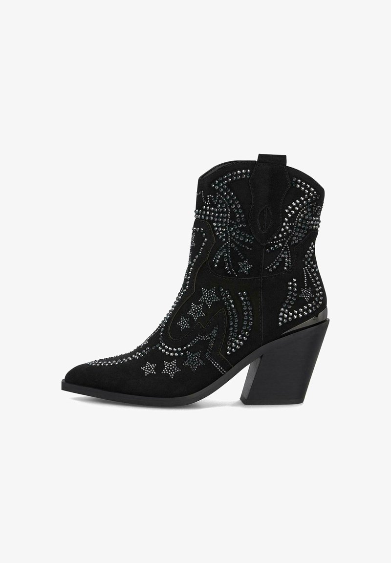 Stivale alla caviglia in suede nero con punta affusolata, caratterizzato da borchie metalliche, motivi a stella e un tacco spesso. Cuciture dettagliate sulla gamba.