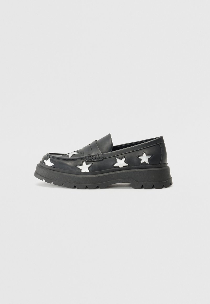 Svarta loafers med vita stjärnmönster, tillverkade av släta läder. Kraftiga gummisulor och en klassisk slip-on-design. Syt detaljer på ovansidan.