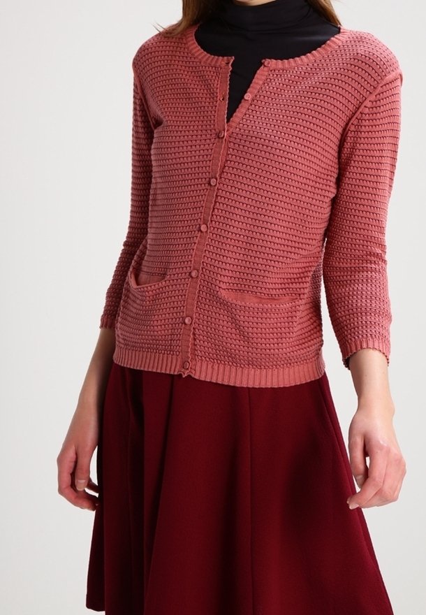 Ljusrosa cardigan med trekvartsärmar, texturerad stickning, rund halsringning, framfickor och knappar nedtill i mitten, tillsammans med en bordeauxfärgad kjol.