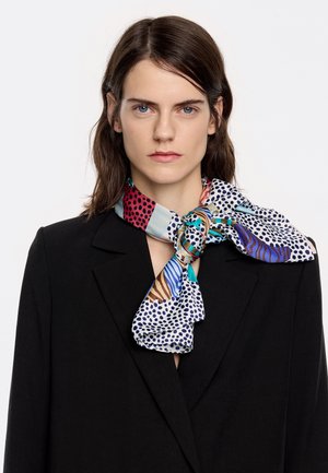 Silk scarf featuring multiple vibrant patterns: polka dots, stripes, and abstract designs. Tied at the neck with a smooth finish.