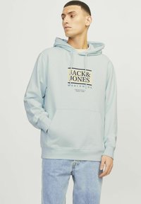Jasnoniebieska hoodie z frontową kieszenią, z czarnym i beżowym logo. Wykonana z miękkiego materiału, z kapturem na sznurki i prążkowanymi mankietami.