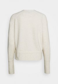 Jasnobezowy skrócony sweter, z miękką teksturą, rękawami raglanowymi i prążkowanym dołem. Gładki materiał z minimalnymi detalami z tyłu.