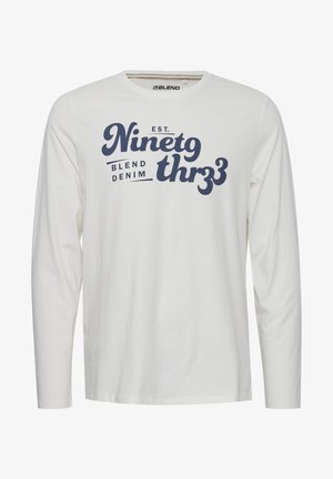 Pikad varrukad valge t-särk, mis on valmistatud puuvillast ning millel on ümmargune kaelus, esiosal on tumesinise graafilise tekstiga disain.