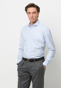 Lichtblauw overhemd, lange mouwen, met knoopsluiting aan de voorkant, gecombineerd met grijze broek en een donkerbruine riem. Gladde stof en een getailleerd ontwerp.