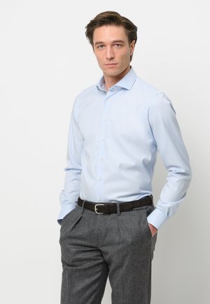 Helles blausehe Hemd, lange Ärmel, knöpfbarer Vorderteil, kombiniert mit grauen Hosen und einem dunkelbraunen Gürtel. Glatte Stoffqualität und figurbetontes Design.