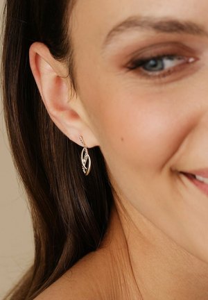 Vergoldete, blattförmige Ohrringe mit filigranen Details und einem subtilen Schimmer, die an einem schlichten Haken hängen. Minimalistisches, aber elegantes Design.