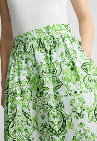 Falda verde estampada con un fondo de menta claro, intrincados diseños florales, cintura elástica y bolsillos laterales.