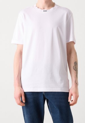Biała koszulka z krótkim rękawem wykonana z gładkiej bawełny. Posiada okrągły dekolt z czarnym logo "BOSS" przy kołnierzu. Prosty, gładki design.
