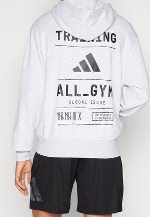 Szara bluza z kapturem z czarnymi nadrukami, w tym logo i tekstem na plecach. Do tego czarne szorty z akcentującym logo.