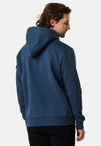 Felpa con cappuccio di colore blu scuro, realizzata in tessuto morbido. Presenta una tasca a marsupio e polsini e orlo a coste. La vista posteriore mostra una vestibilità rilassata.