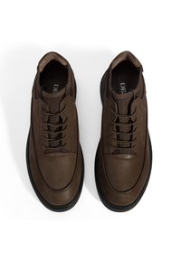Bruine leren schoenen met een gladde afwerking, vetersluiting, ronde neus en zwarte rubberen zolen. Heeft een zachte binnenvoering.