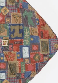 Tela de patchwork multicolor con varios motivos de animales y plantas; presenta puntadas texturizadas y una mezcla de formas en tonos tierra.