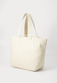 Beige canvas tote bag with two sturdy handles, rectangular shape, and a simple, unembellished design. Suitable for everyday use.