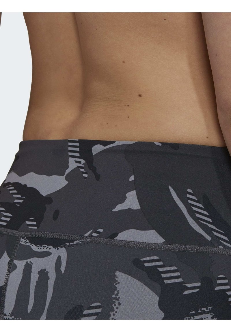 Los pantalones cortos deportivos de camuflaje gris cuentan con una cintura ajustada con acentos en negro y blanco y una textura de tela lisa y elástica.