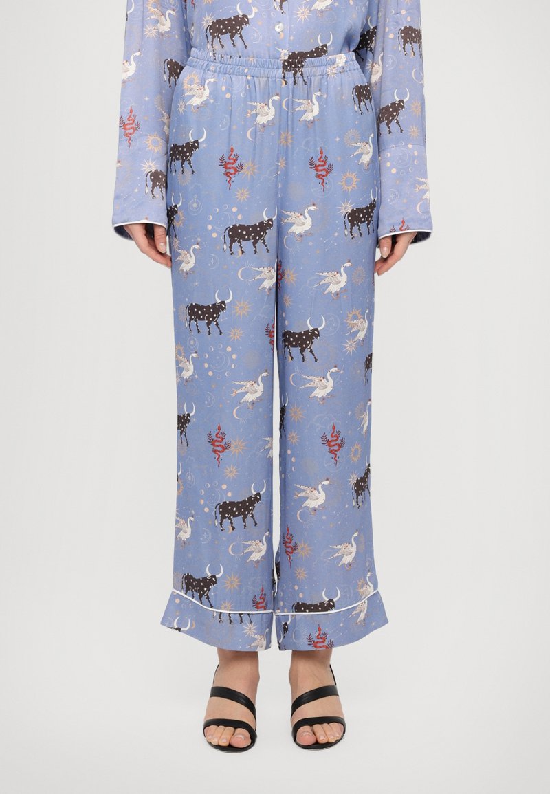 Pantaloni de pijama de culoare albastru deschis, cu un model întreg de unicorni și vaci, având talie elastică, formă evazată și detalii albe la tiv.