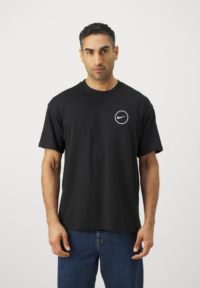 Schwarzes Baumwoll-T-Shirt mit einem weißen runden Logo auf der linken Brust. Kurze Ärmel und klassischer Rundhalsausschnitt. Glatte Textur.