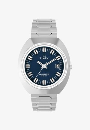 Reloj de pulsera de cuarzo con caja y pulsera de acero inoxidable plateado, esfera azul marino, marcadores de hora blancos y ventana de fecha a las 3 en punto.