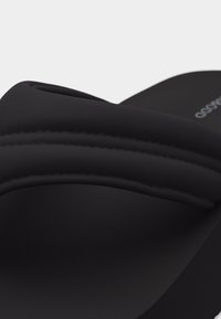 Μαύρο ανατομικό σανδάλι τύπου σλάιντ με φαρδιά μαξιλαρωμένη λωρίδα και εμφανείς ραφές.