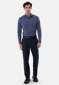 Navy- und weiße gestreifte Hemd mit Knopf und Kragen, kombiniert mit dunklen Hosen und schwarzen Schuhen. Hat eine schmale Passform und Standardmanschetten.