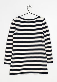 Langarmshirt mit navyblauen und weißen horizontalen Streifen, aus weicher Baumwolle. Rundhalsausschnitt und leicht lockere Passform. Hängt an einem schwarzen Haken.