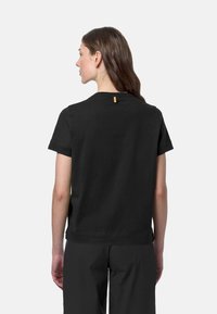 T-shirt in cotone nero con maniche corte, colletto rotondo e una piccola etichetta gialla accentuata sul retro. Tessuto morbido e vestibilità comoda.