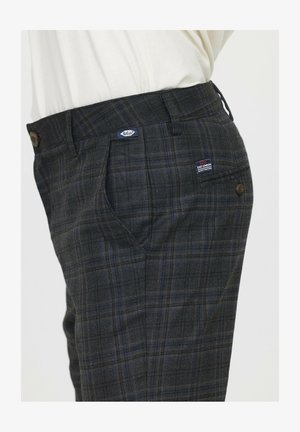 Pantalons à carreaux gris avec des accents bleus et jaunes, présentant des poches avant, une taille avec un bouton, et une étiquette sur le côté avant.
