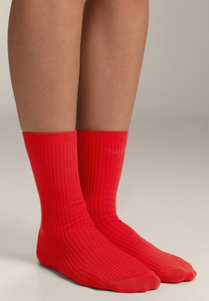 Calze rosse a coste di lunghezza media fino al polpaccio, con una texture liscia e aperture elasticizzate per il comfort. Nessun motivo o dettaglio distintivo visibile.