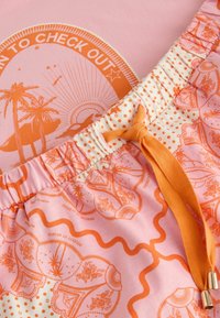 Tela estampada rosa y naranja con diseños de palmeras y sol, con cintura elástica y cordón naranja.