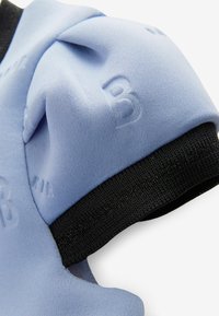 Světle modrá sportovní tkanina s texturovanými vzory a černým elastickým lemem. Obsahuje vyražená čísla na povrchu, která označují velikost.