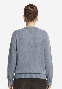 Maglione blu in morbido tessuto a maglia, con scollo rotondo, polsini e orlo a coste, caratterizzato da un design semplice e senza motivi visibili.