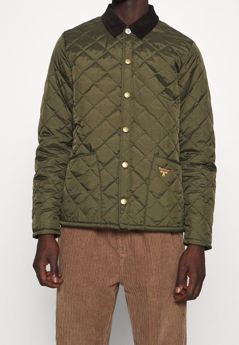 Vadderad grön jacka med brunt manchesterkrage, guldfärgade knappar och två framfickor. Har en liten logotyp på vänster bröst.