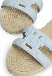 Ljusblå lädersandaler med texturerade, överlappande remmar. Jute-sulan har ett spiralmönster. Minimalistisk logotypdetalj på remmarna.