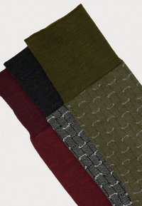 Tri par sock: temnozeleno z blagimi vzorci, črno in burgundsko. Narejeni so iz teksturiranega pletenega materiala z elastičnimi manšetami.