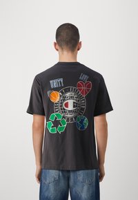Black cotton t-shirt featuring colorful graphics on back: a globe, basketballs, hearts, and recycling symbols with text "UNITY" and "LOVE."