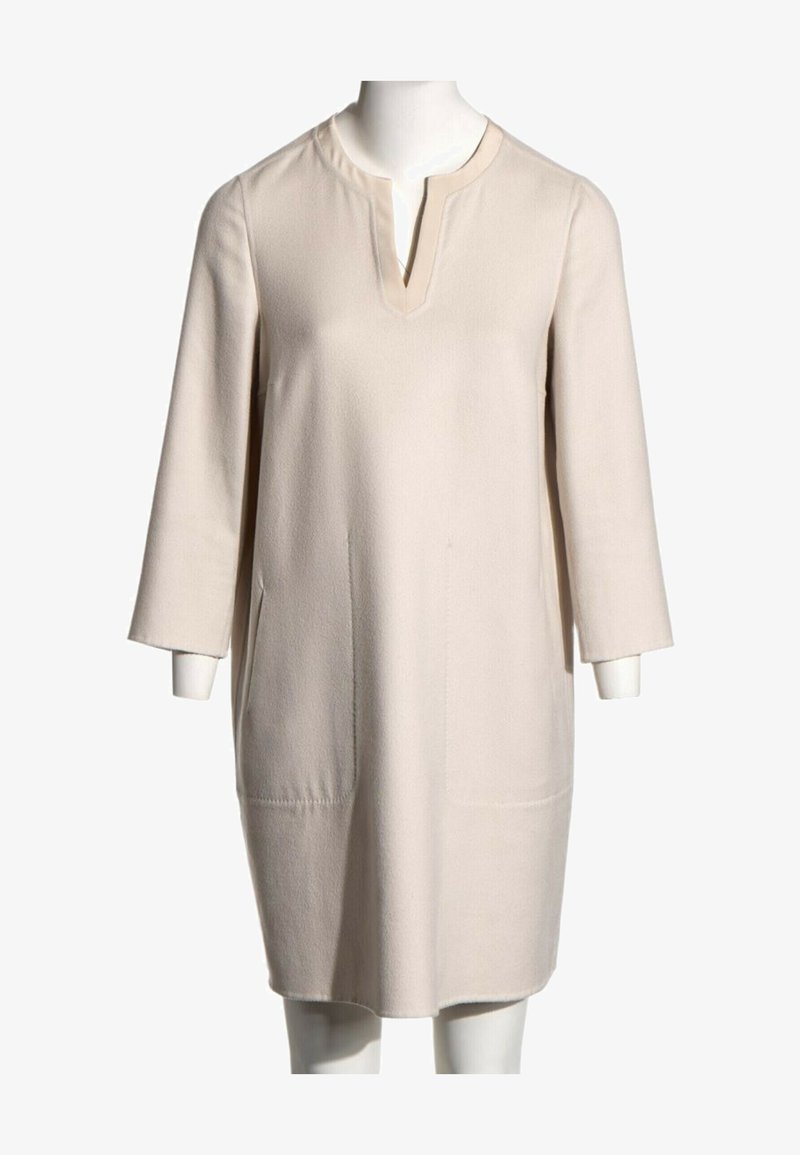Robe crème longueur genou avec manches trois-quarts et encolure ronde avec une petite fente en V.