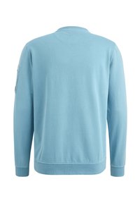 Hellblaues Sweatshirt aus Baumwolle mit langen Ärmeln, Rundhalsausschnitt und einer Tasche am linken Ärmel. Weiche Textur, lässige Passform.
